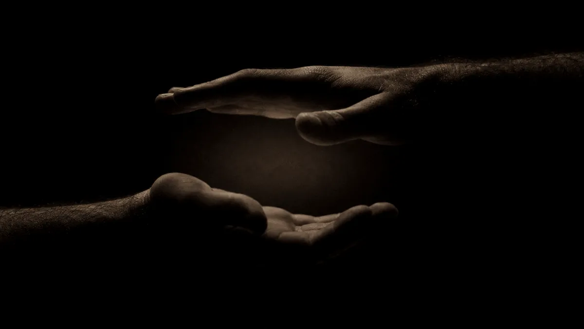 Hands held in a quiet practice over a small pool of light.